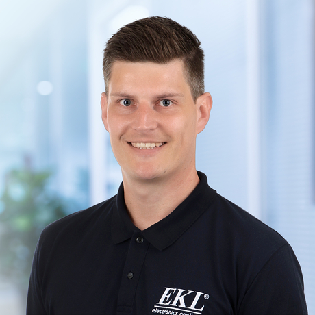Das Bild zeigt einen lächelnden Mann in einem schwarzen Poloshirt mit dem Logo 