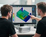 The image shows two individuals discussing a computer hardware design displayed on a monitor, with a heat map visualization overlaid on a graphics card.